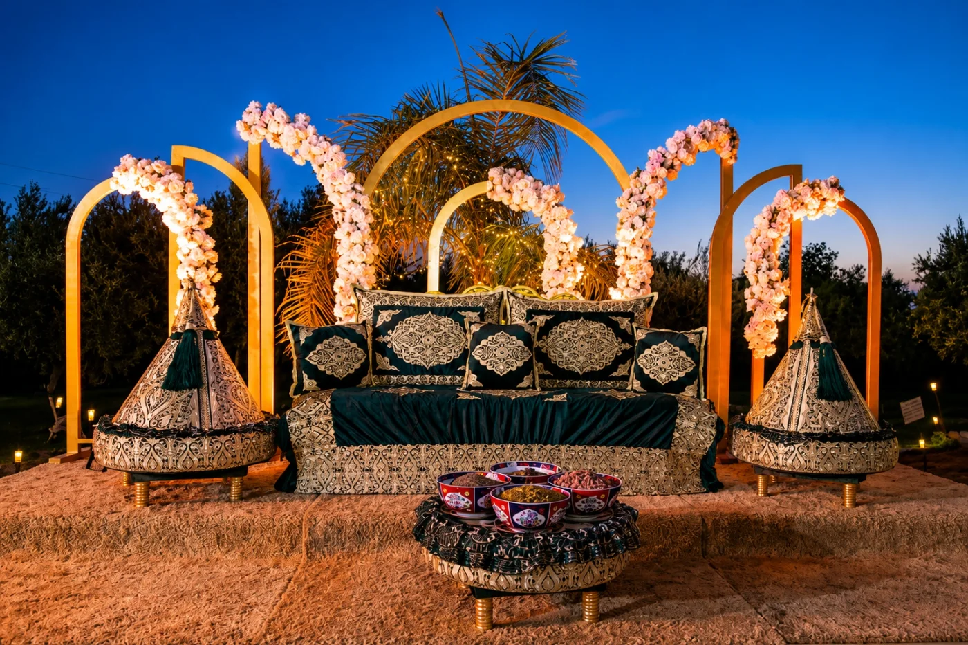 Décor de mariage oriental à la Villa Dar Moudar — banquette dorée, coussins brodés et arches de roses, organisation de mariage à Marrakech